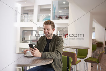 Young man using his smartphone in a modern university cafe