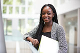 Smiling young black female student in university foyer