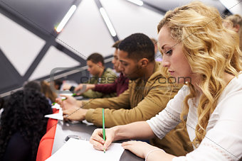 Female student taking notes in a university lecture theatre