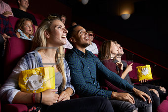 Young Couple In Cinema Watching Film And Eating Popcorn