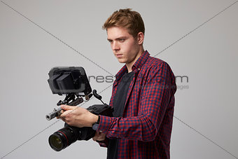Studio Portrait Of Male Videographer With Film Camera