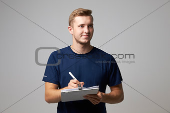 Studio Portrait Of Male Sports Coach With Clipboard