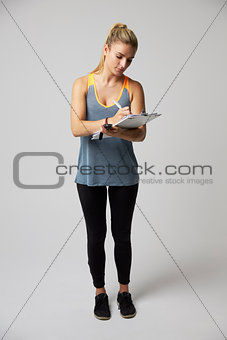 Studio Portrait Of Female Sports Coach With Clipboard