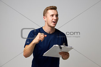 Studio Portrait Of Male Sports Coach With Clipboard