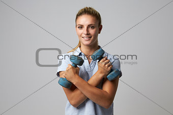 Studio Portrait Of Female Sports Coach Holding Weights