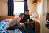 Male Students Working In Bedroom Of Campus Accommodation
