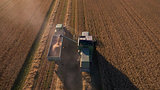 Aerial View As Tractor Collects Wheat From Combine Harvester