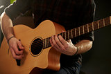 Close Up Of Man Playing Acoustic Guitar In Studio