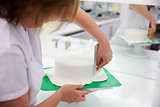 Close Up Of Woman In Bakery Decorating Cake With Royal Icing