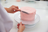 Close Up Of Woman In Bakery Decorating Cake With Icing
