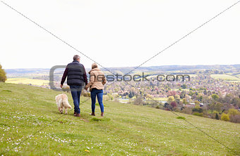 Rear View Of Mature Couple Taking Golden Retriever For Walk