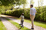 Rear View Of Father And Son Walking In Summer Countryside