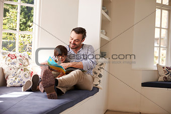 Father And Son Reading Story At Home Together