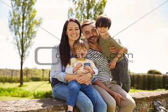 Family Sitting On Wall During Walk In Summer Countryside