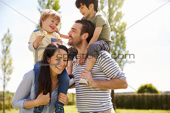 Parents Giving Sons Ride On Shoulders During Walk