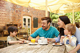 Family Sitting At Outdoor Cafe Table Having Lunch