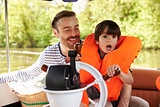 Father And Son Enjoying Day Out In Boat On River Together