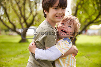 Two Brothers Hugging In Park Together