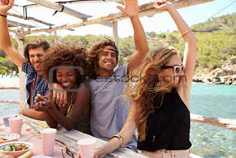 Two couples in a row at a table by the sea looking to camera