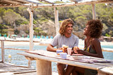 Young couple eating at a table by the sea look at each other
