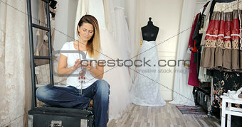 Woman in tailor's shop with phone