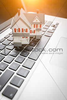 Miniature House And Laptop Computer Resting on Desktop.