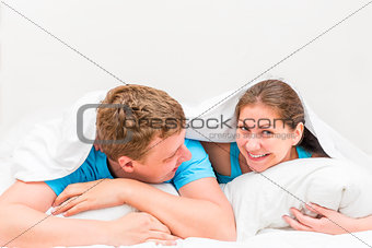Young beautiful couple in bed under a blanket