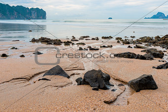 Large stones in the sand against the background of the sea, rain
