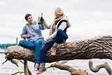 couple sitting on tree stump at the riverside drinking beer