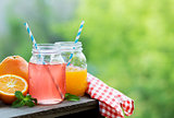 Grapefruit and orange juice in glass jars in the open air.
