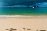 Sandy beach with sun rays before a tropical rain