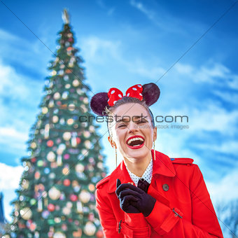 smiling stylish woman near big Christmas tree in Disneyland