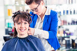 Hairdresser styling woman hair in shop