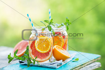 Grapefruit and orange water in glass jars in the open air.