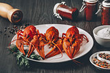 Three boiled fresh crawfish in white plate with green herbs