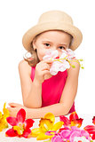 girl in the hat smelling a branch of pink orchids on a white bac