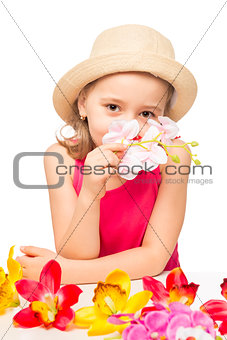 girl in the hat smelling a branch of pink orchids on a white bac