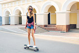 summer holidays, extreme sport and people concept - happy girl riding skateboard on city street