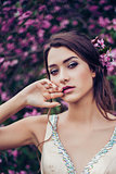 Portrait of young beautiful woman posing among spring blossom trees.