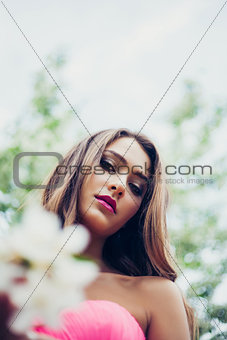 Portrait of young beautiful woman posing among spring blossom trees.