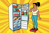Diet. Young woman on scales, stand next to the refrigerator with
