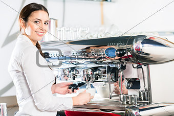 Young waitress using an automatic coffee machine