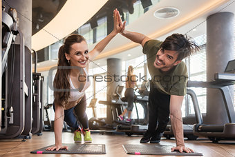Young man and woman giving high five from basic plank pose durin