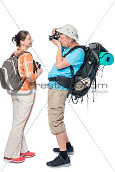 Man tourist with a backpack photographing his girlfriend isolate