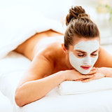 Relaxed young woman with revitalising mask on face laying on mas