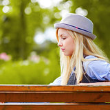 Thoughtful hipster girl sitting on bench in the park