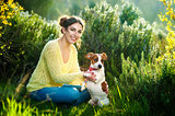 Girl walking with a hunting dog - the Jack Russell Terrier . Close-up. Spring. Copy space.