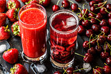 Fresh strawberry smoothie and Detox water with cherries in two glasses on a gray background. Healthy detox drinks.