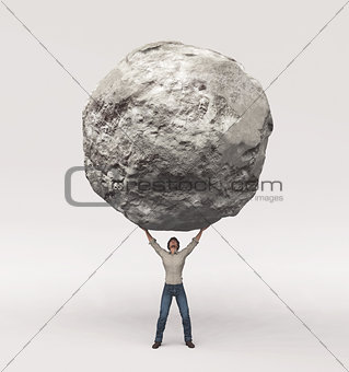 Young man pick up a large rock 