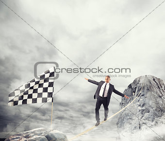Business concept of businessman who overcome the problems reaching the flag on a rope
